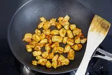 Hähnchenbrustfiletstücke mit Currypulver gewürzt, in der Pfanne angebraten für ein asiatisches Reisgericht