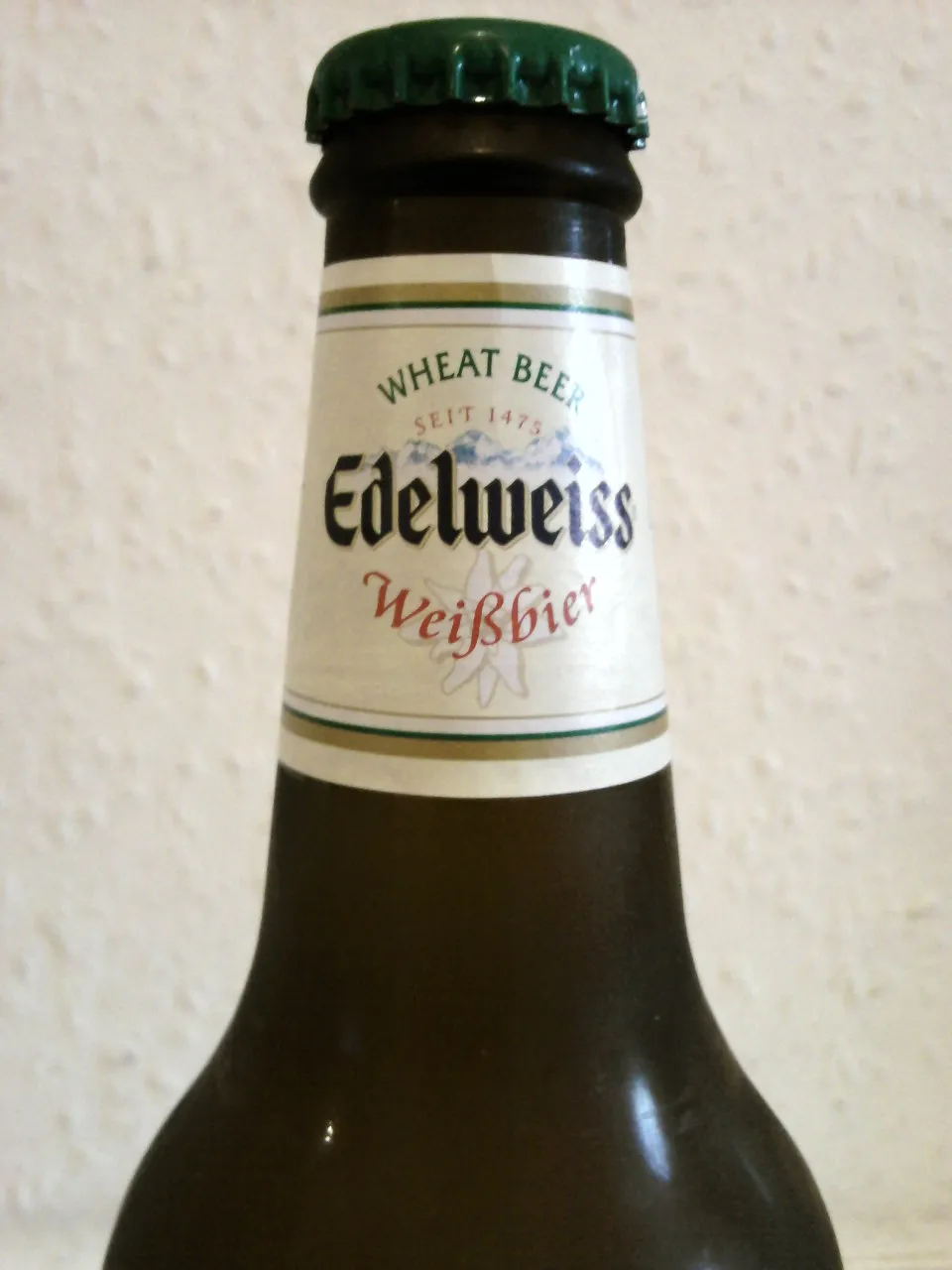 Halslabel des Edelweiss Weizenbiers mit Jahreszahl 1475 und Alpenmotiv