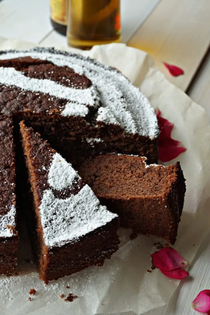 Hand hält ein Stück Schokoladenkuchen mit Bierflasche im Hintergrund