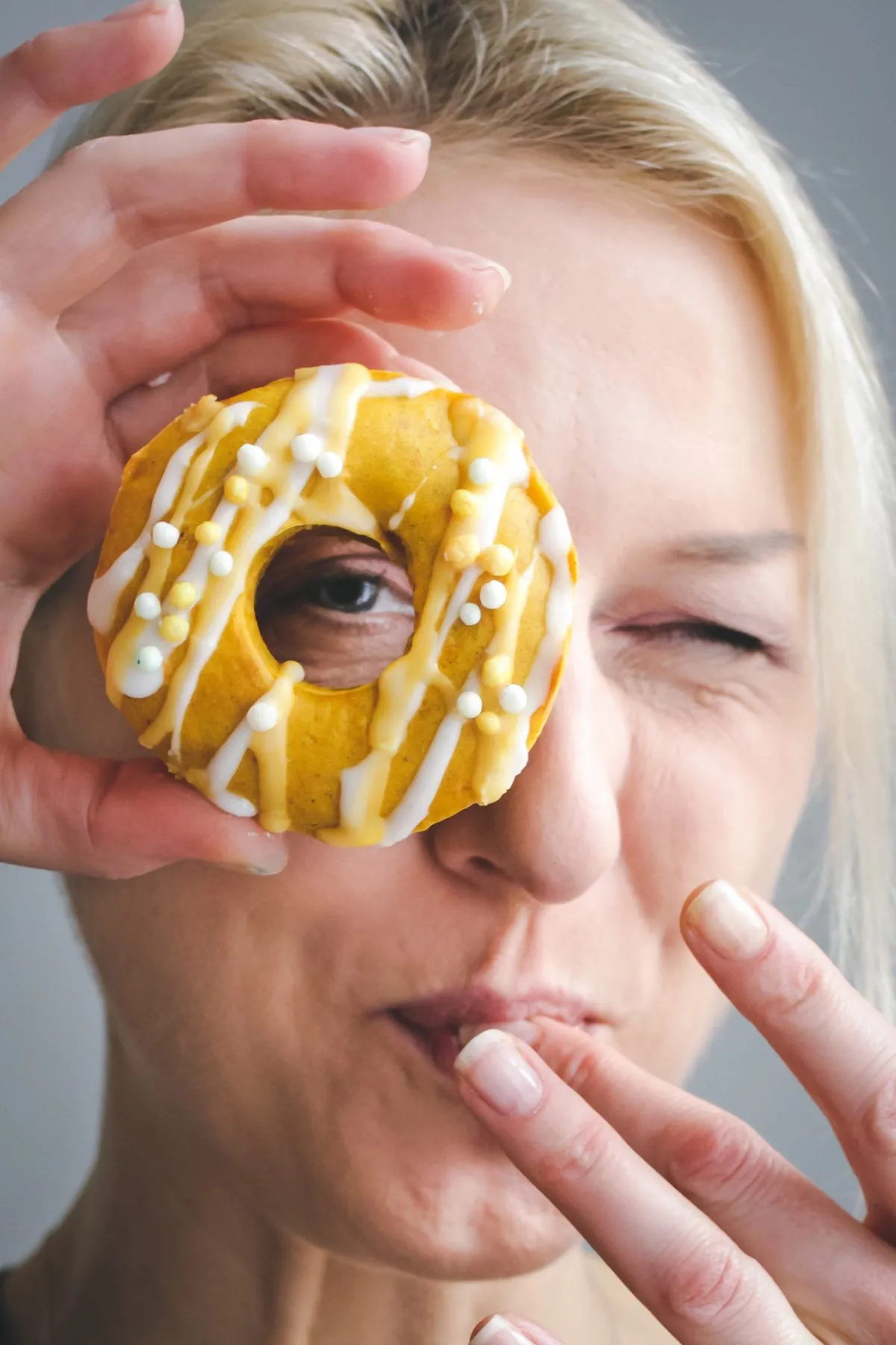 Hand hält einen veganen Kürbis-Donut mit Zitronenglasur, zubereitet mit Dr. Oetker Creme VEGA