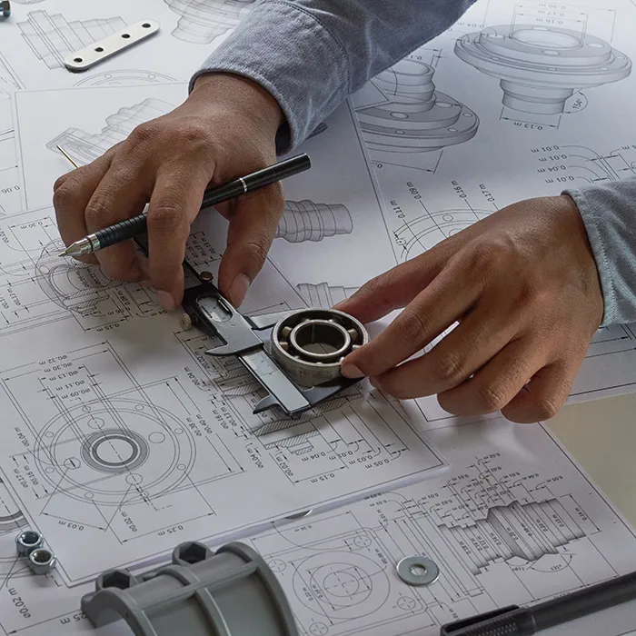 Hand hält Lineal über technischen Zeichnungen für präzise Konstruktion.
