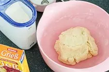 Hände kneten Kartoffelteig mit Mehl und Grieß zu einer glatten Masse für selbstgemachte Gnocchi.