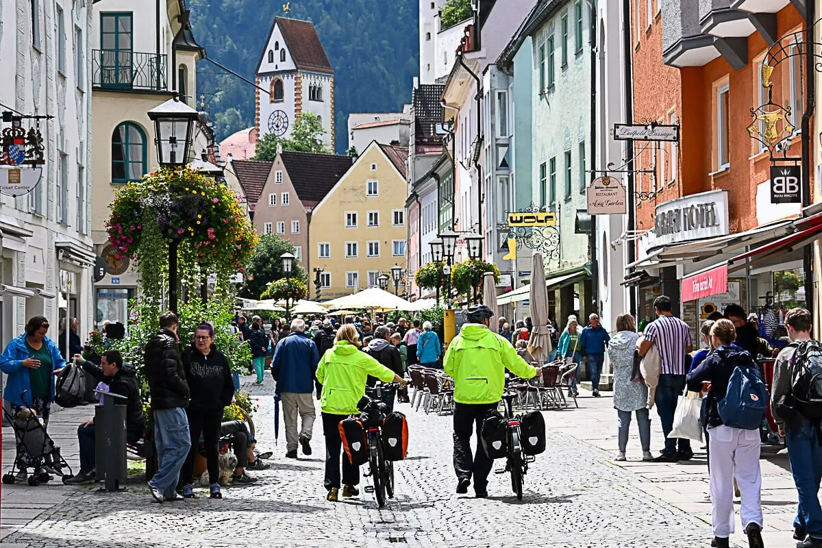 Hauptstraße Füssen: Lebhaftes Treiben in der Einkaufsstraße mit dem Hohen Schloss im Hintergrund