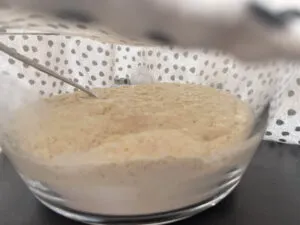 Hefeteig für Zwiebelkuchen, der in einer Schüssel ruht, mit einem Tuch abgedeckt