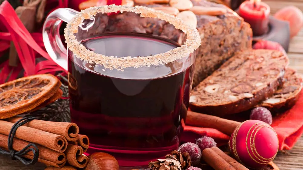 Heißer Jagertee in einer rustikalen Tasse, umgeben von winterlicher Dekoration