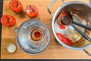 Heißes, selbstgemachtes Ajvar wird in sterile Gläser abgefüllt, um es haltbar zu machen