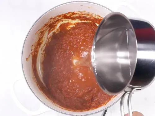 Heißes Wasser in die Tikka Masala Sauce gießen und verrühren