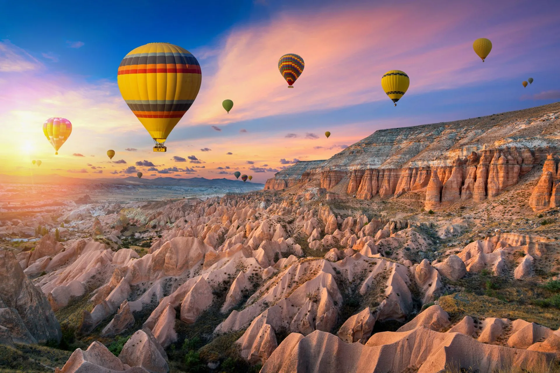 Heißluftballons schweben über den einzigartigen Felsformationen von Kappadokien im Göreme Nationalpark in der Türkei bei Sonnenaufgang