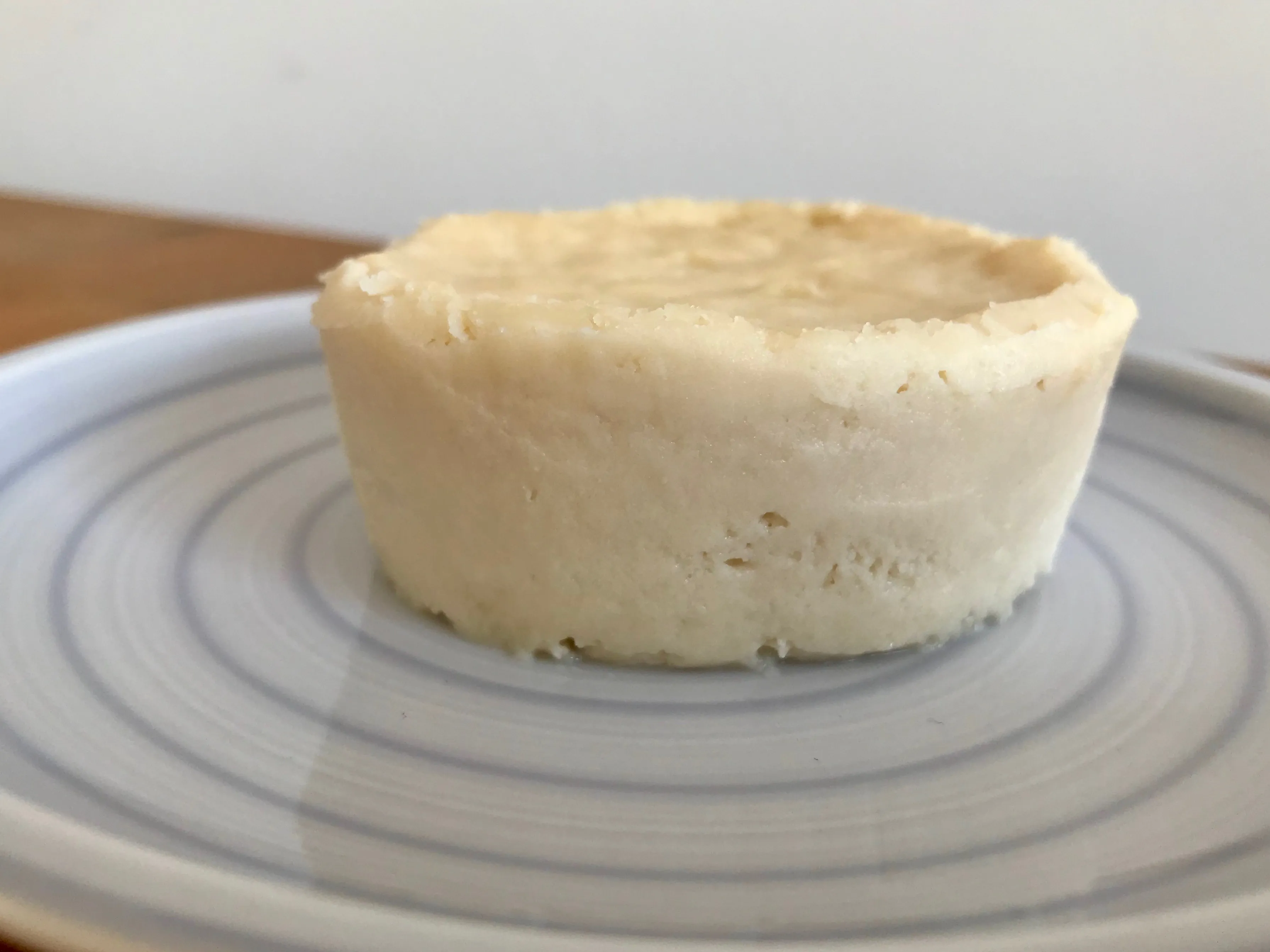 Helle, gelbliche vegane Käsekuchenmasse mit matter Oberfläche, die gebacken wurde und sich leicht bräunt