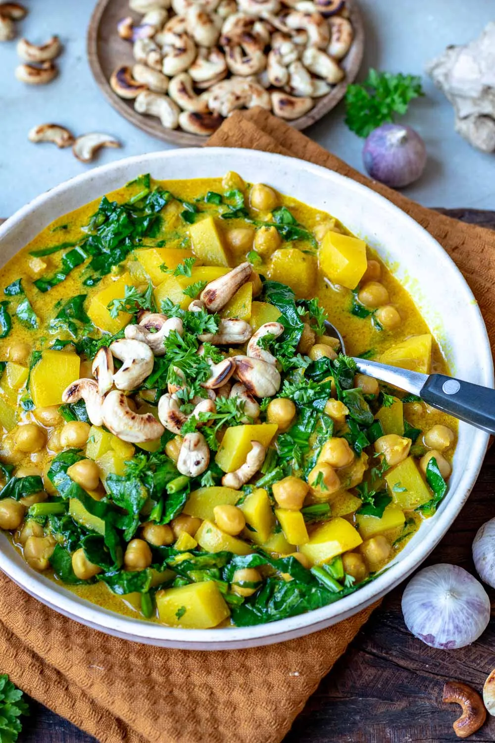 Herzhaftes Kichererbsen-Kartoffel-Curry mit frischem Spinat in einer dunklen Schale