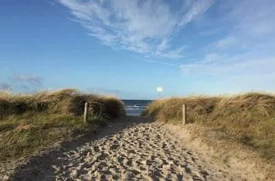 Holzsteg führt zu einem weiten Strand mit Meerblick an der Ostsee