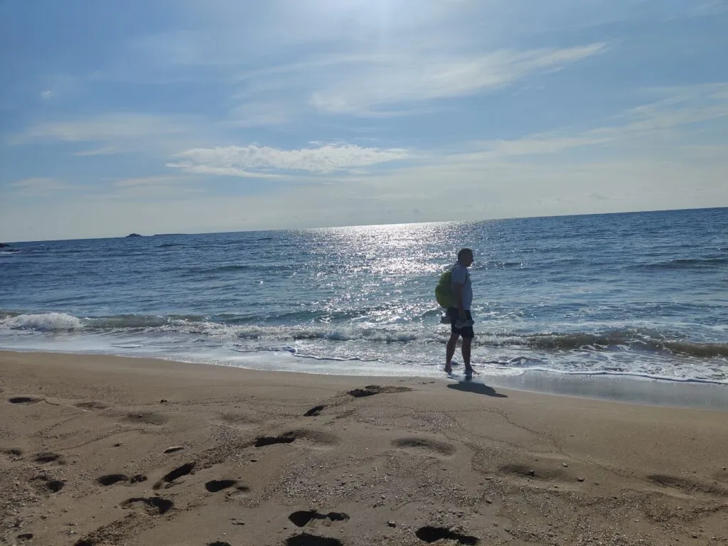 Idyllische Szene am Sandstrand einer griechischen Insel mit Blick auf das kristallklare Wasser