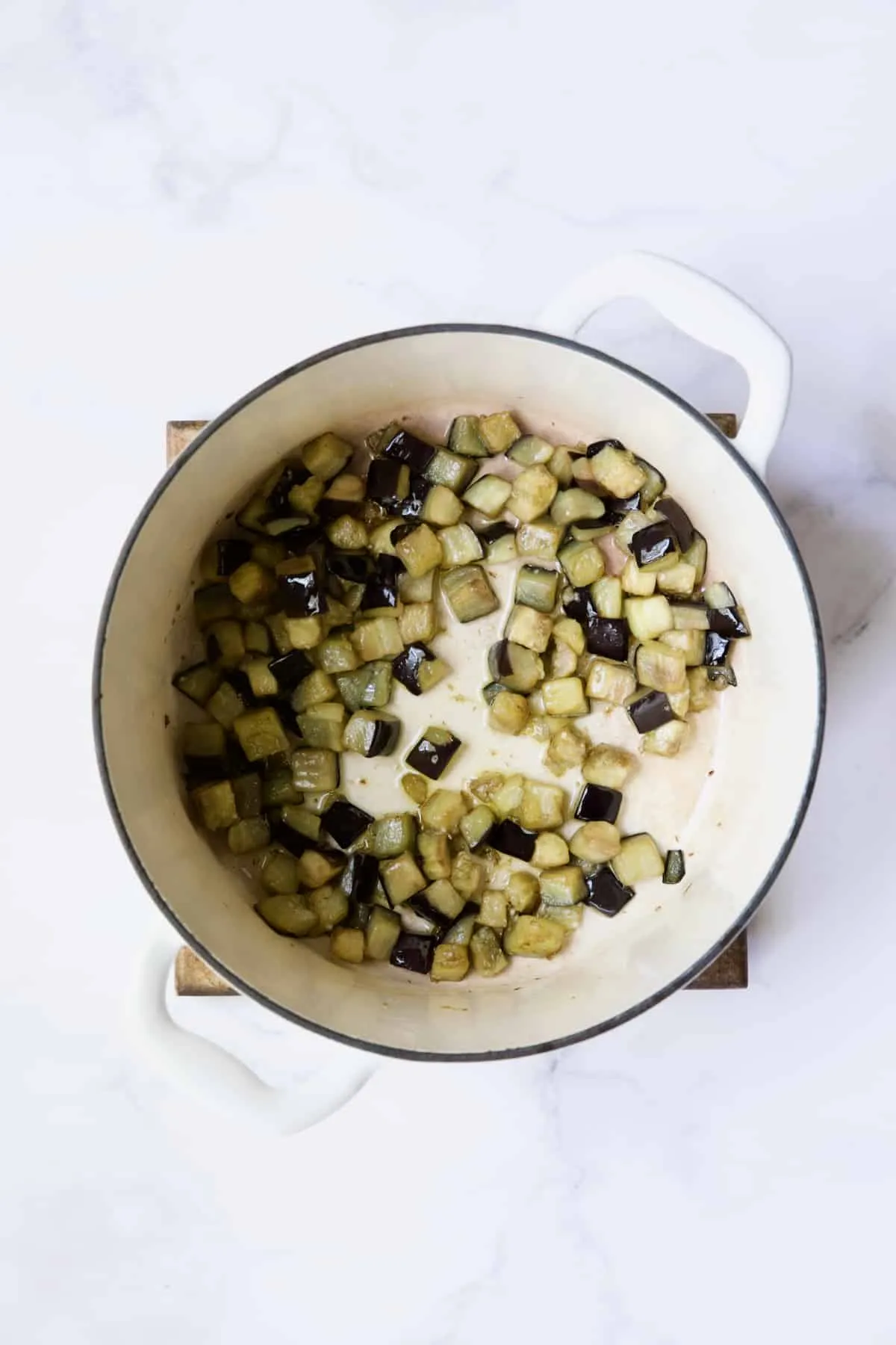 In einem weißen Dutch Oven wird Aubergine gekocht.