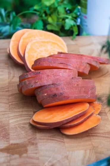 In Scheiben geschnittene Süßkartoffel wird sorgfältig in gleichmäßige, fingerdicke Scheiben geschnitten, ideal für das Süßkartoffel grillen.