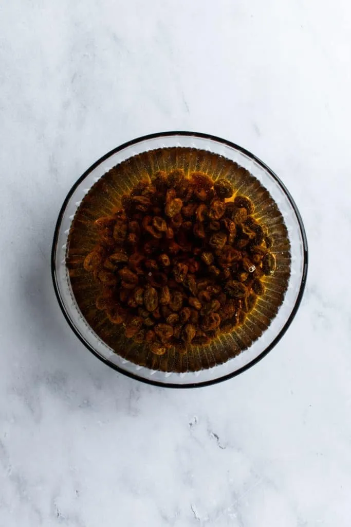 In warmem Wasser eingeweichte Rosinen in einer Glasschüssel, vorbereitet für den Hefeteig des Osterkranzes.