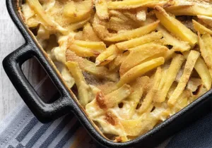 Janssons frestelse: Schichtweise zubereiteter Kartoffelauflauf mit Zwiebeln und eingelegten Sprotten vor dem Backen, bereit für den Ofen.
