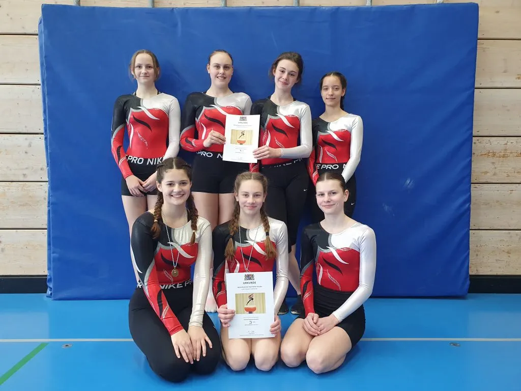 Junge Turnerinnen jubeln nach erfolgreichem Geräteturn-Wettkampf