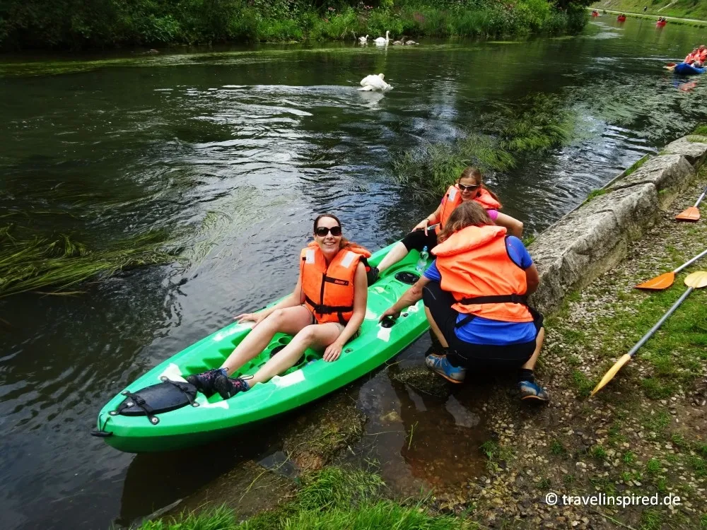Kajakfahrer legen am Ufer der Pegnitz an und vermeiden die Nähe eines Schwanenvaters