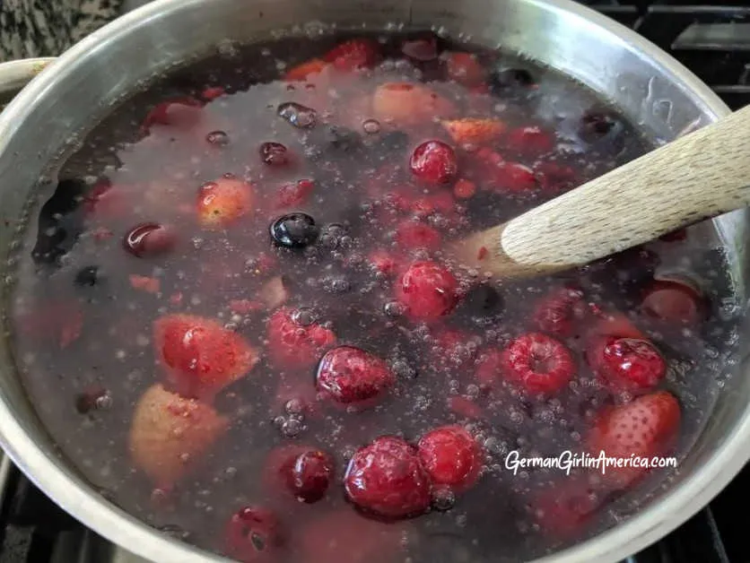 Kaltschale mit frischen Beeren und Kirschen, garniert mit Minze. Der Fokus liegt auf der Textur der Suppe und den leuchtenden Farben der Früchte. Alt-Text: Erfrischende Kaltschale mit Beeren und Kirschen: Ein perfektes Sommergericht