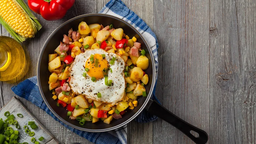 Kartoffelpfanne mit Spiegelei in einer gusseisernen Pfanne, appetitlich angerichtet für ein schnelles, glutenfreies Mittagessen.