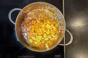 Kartoffelwürfel in die Suppe hineingeben.