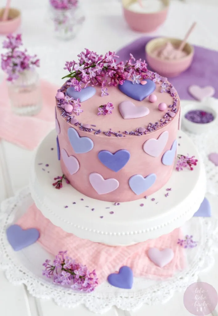 Käse-Sahne-Torte liebevoll dekoriert mit lila Flieder und altrosafarbener Buttercreme, perfekt für den Muttertag