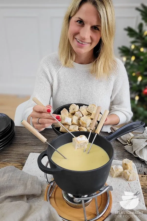 Käsefondue mit verschiedenen Beilagen auf einem Holztisch