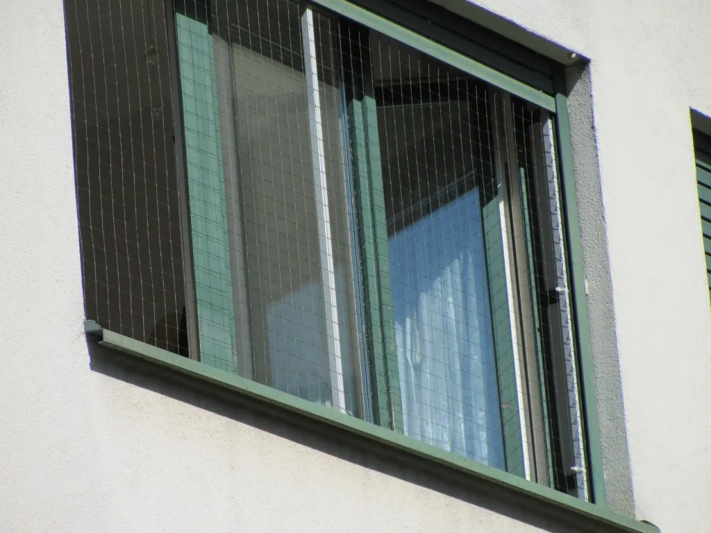 Katzenschutznetz an einem Wohnbalkon, eine Katze sitzt geschützt im Freien