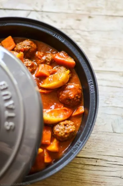 Kefta-Tajine mit Süßkartoffeln und Zitronenspalten köchelt im traditionellen Kochgeschirr.