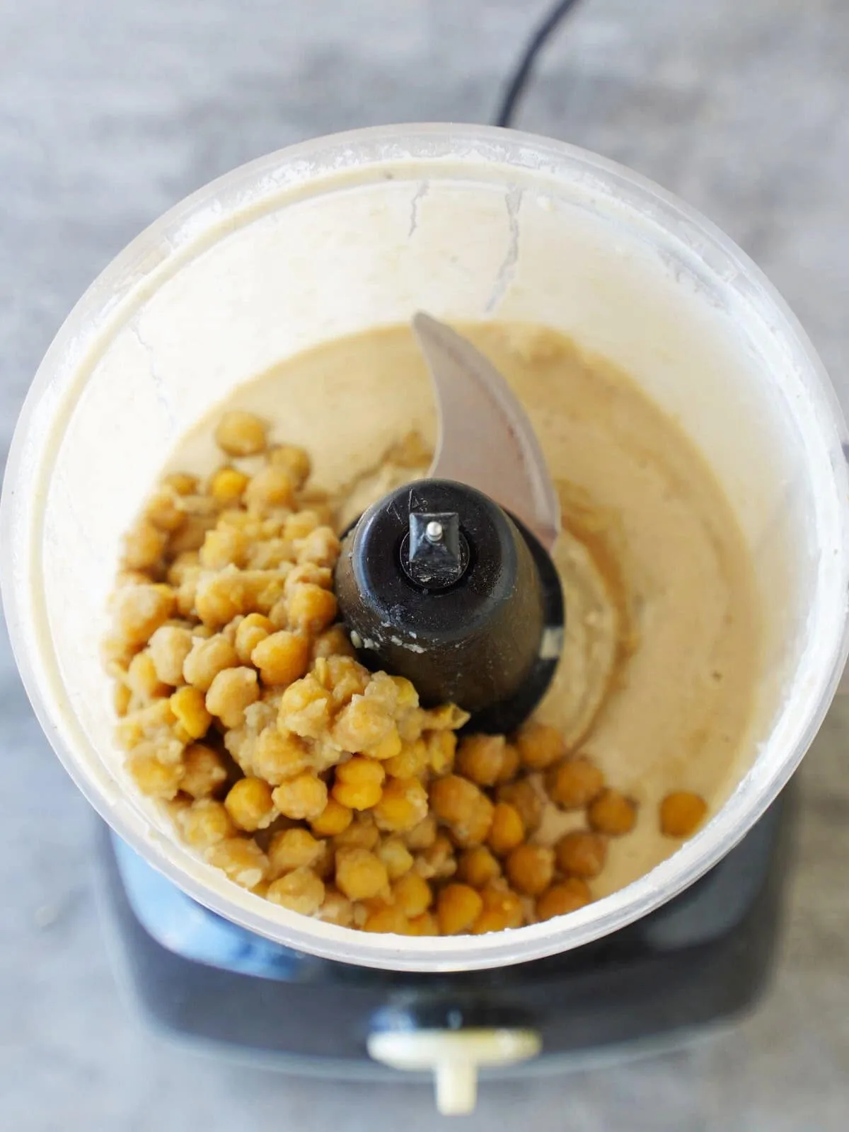 Kichererbsen, Tahin und weitere Zutaten werden in einer Küchenmaschine zu einer glatten Masse püriert