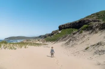 Kind spielt an einem Strand im Robberg Nature Reserve