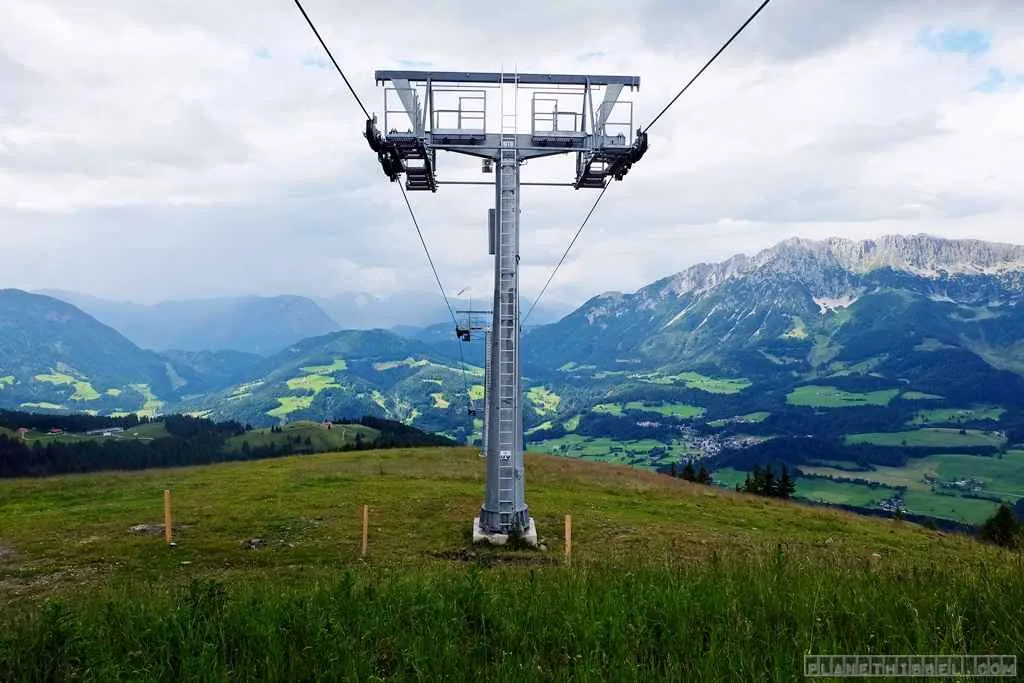 Kind spielt auf einem hölzernen Spielplatz in den Kitzbüheler Alpen vor beeindruckender Bergkulisse