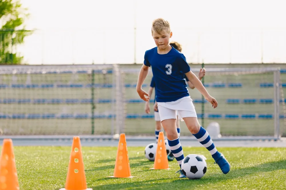 Kind spielt Fußball auf einem grünen Rasenplatz in Deutschland