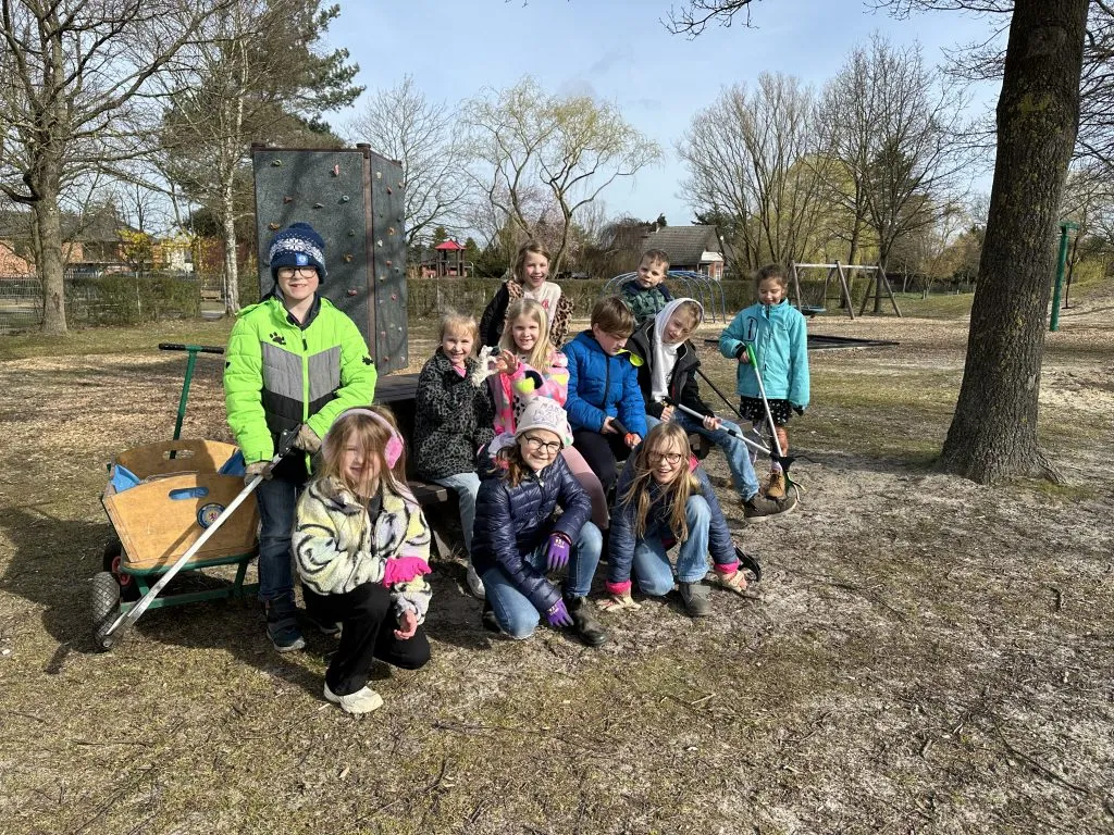 Kinder sammeln mit Müllzangen, Handschuhen und Bollerwagen Müll im Dorf ein, als Teil ihres Nachhaltigkeitsprojekts.