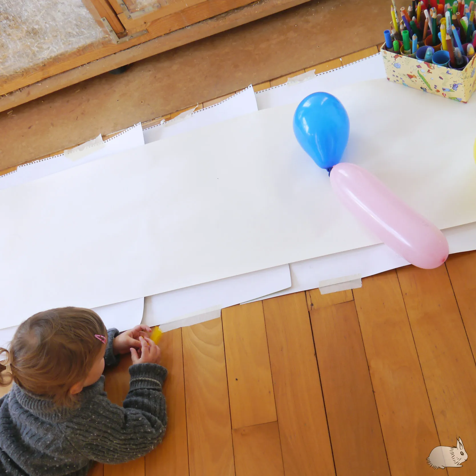 Kinder spielen mit Luftballons und bemalen Papier auf dem Boden zum 3. Geburtstag