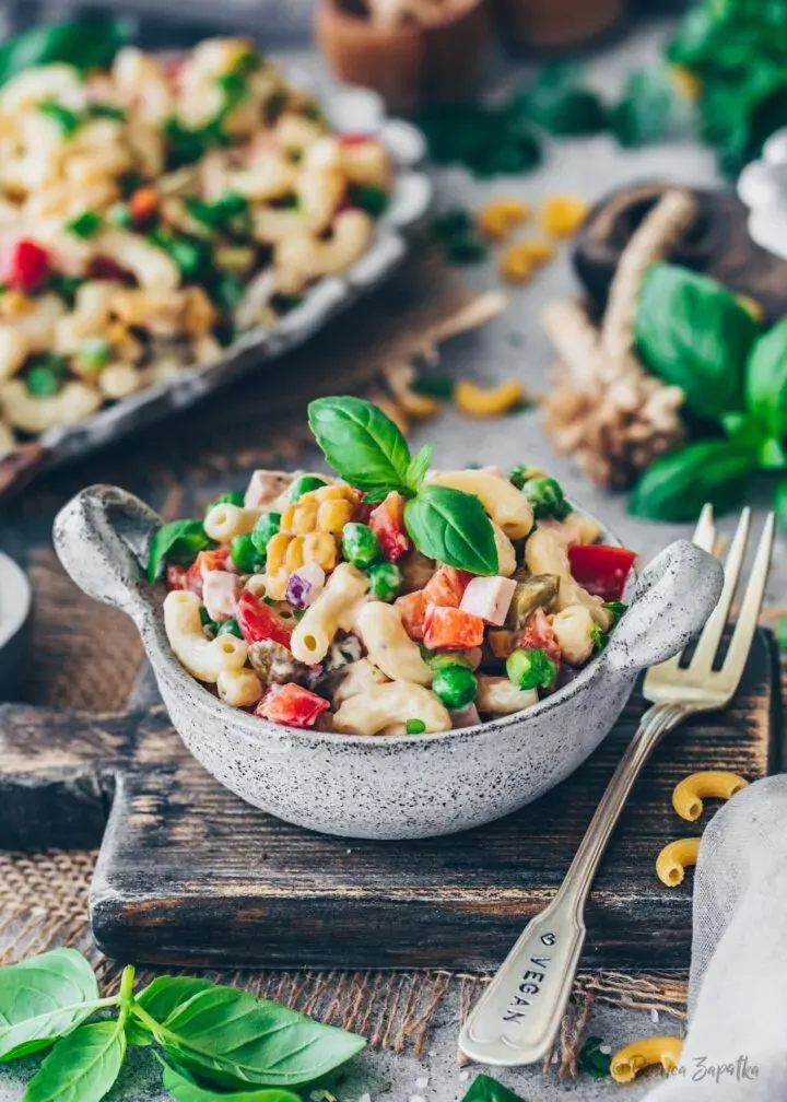 Klassischer veganer Nudelsalat mit Erbsen, Gurken, cremigem Dressing und frischem Basilikum als Garnitur.