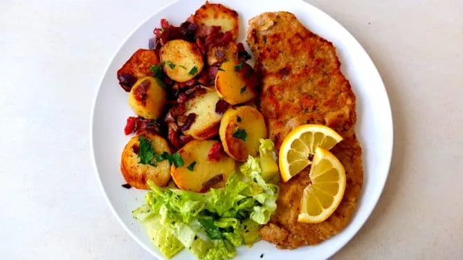 Klassisches Wiener Schnitzel serviert mit knusprigen Bratkartoffeln als Beilage