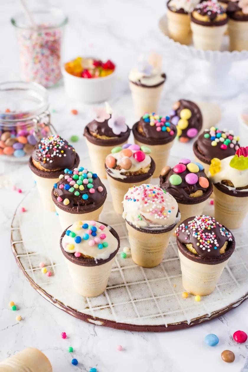 Kleine Kuchen im essbaren Waffelbecher, dekoriert mit Smarties und Streuseln