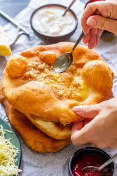 Knoblauch und Olivenöl werden auf einem frisch gebackenen Langos verteilt