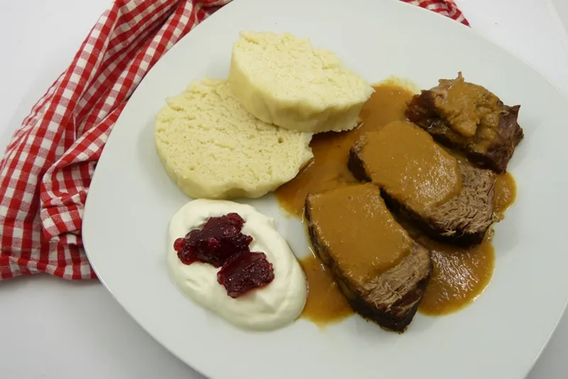 Knödel mit zartem Rindfleisch und feiner Rahmsauce, garniert mit Preiselbeeren