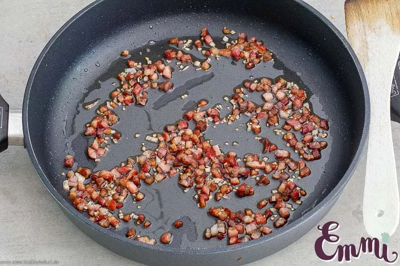 Knusprig angebratener Pancetta oder Speck in einer heißen Pfanne – eine Schlüsselzutat für die cremige Carbonara Soße.