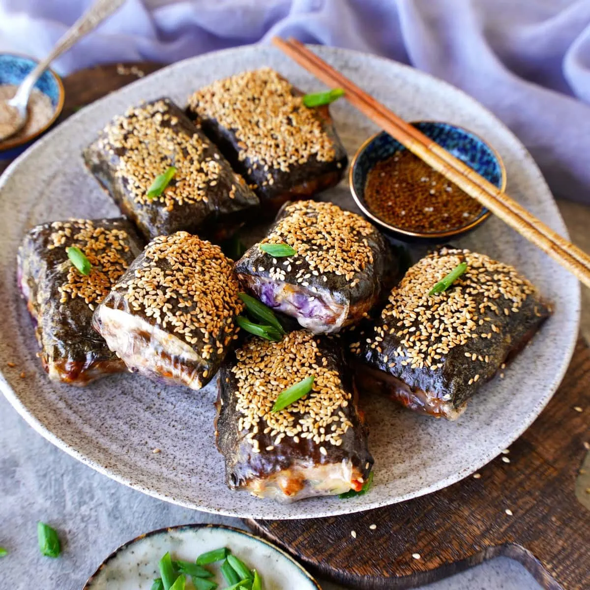 Knusprige Reispapier-Dumplings mit Nudel- oder Sushi-Reis-Füllung auf einem Teller, serviert mit Dip, ein sättigendes veganes Mittagessen.