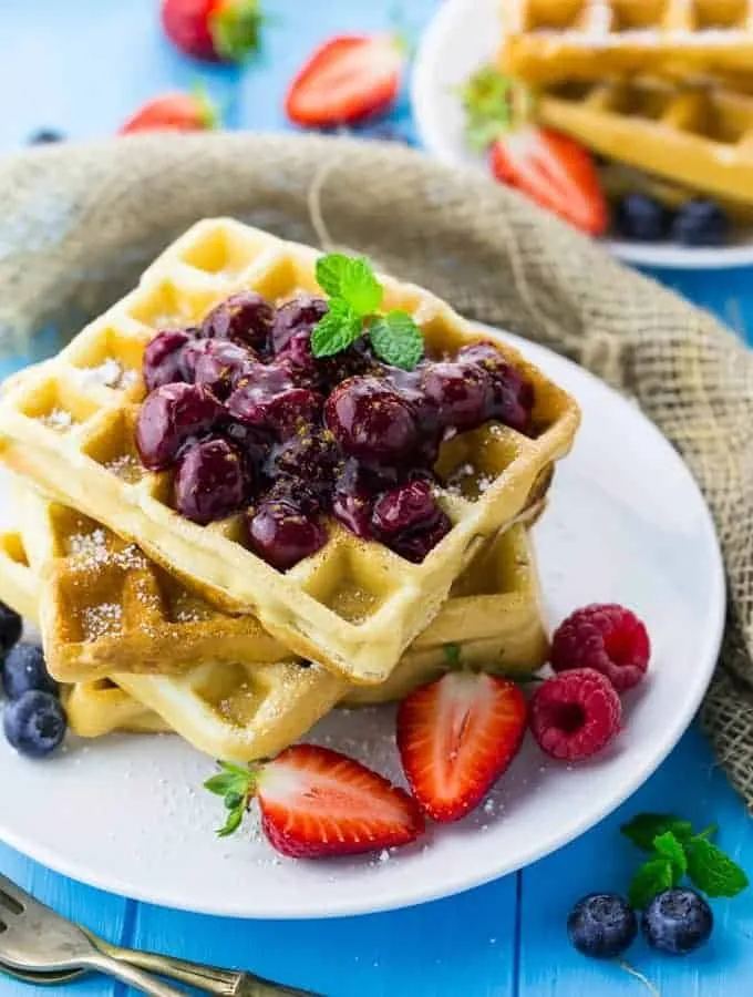 Knusprige vegane Waffeln mit frischer Kirschsauce auf einem hellen Teller, bereit zum Genießen.