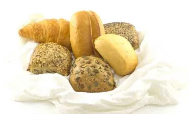 Korb gefüllt mit einer Auswahl an frischen Brötchen, Brezeln und Croissants für eine Probelieferung