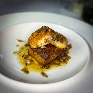 Köstlicher Schweinebauch mit Jakobsmuscheln, ein innovatives Gericht des Cochon Restaurants, das die deutsche Liebe zu Schweinefleisch reflektiert.