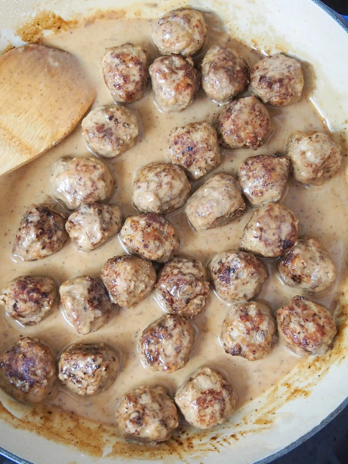 Köttbullar in der cremigen Sahnesauce vorsichtig umrühren, um sie zu erwärmen