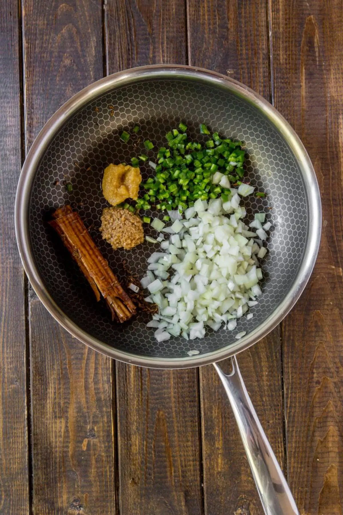 Kreuzkümmel, Zimtstange, Zwiebel, grüne Chili, Knoblauch und Ingwer werden in einer Pfanne temperiert für ein aromatisches Indisches Dal.