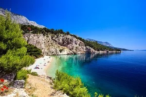 Kroatische Küstenlandschaft mit azurblauem Meer und Felsformationen, ein beliebtes Ziel für Badeurlaub im Juli.