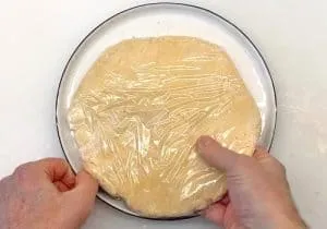 Kugel aus Zwiebelkuchen-Mürbeteig, in Frischhaltefolie eingewickelt zum Kaltstellen