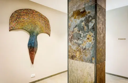 Kunterbunte abstrakte Wandkunst neben einer Steinsäule im Wellnesshotel Klosterhof in Bayern.